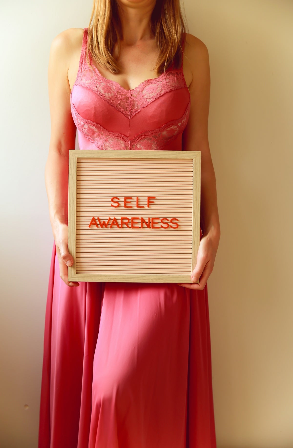 Woman holds a sign that says self awareness